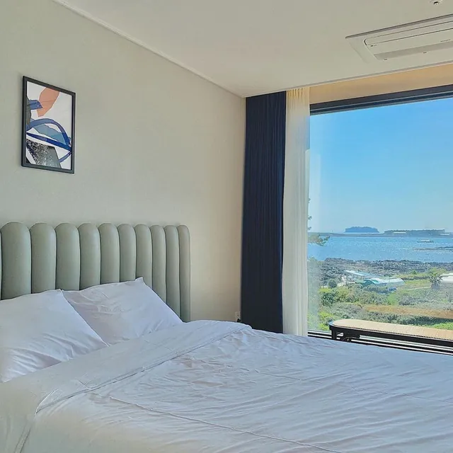 A guest room where the sea and an island fill the large window beyond the bed
