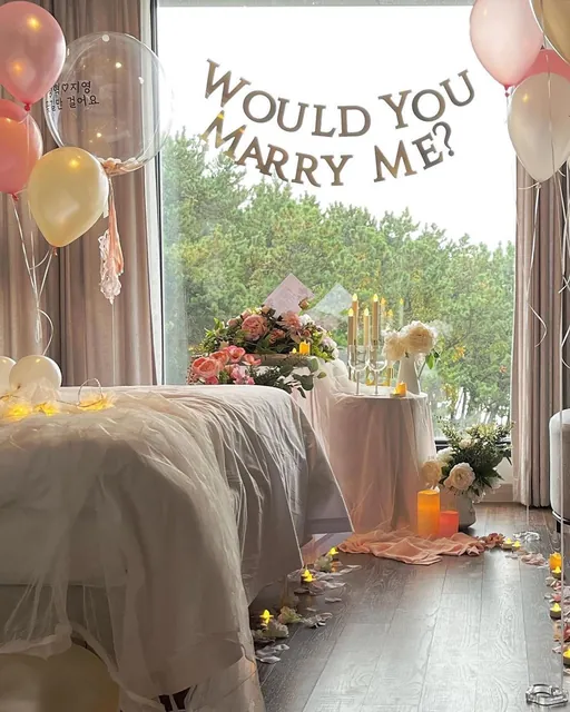 A guest room decorated for a proposal with balloons, flowers and a Would you marry me sign
