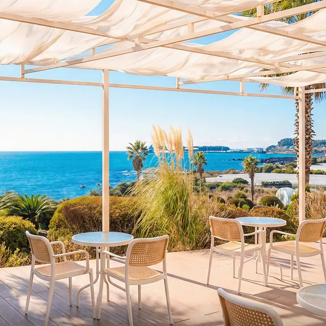 The Boraed Bakers terrace under white sail shades, looking out to sea