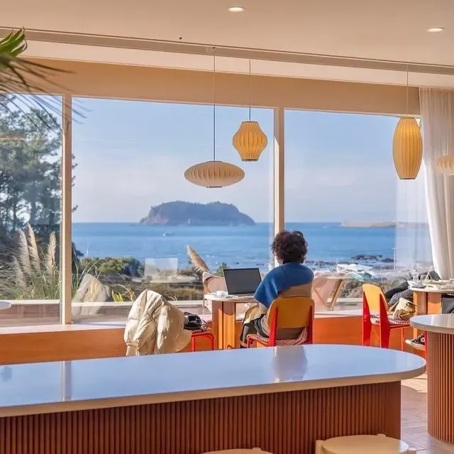 A guest relaxing at a window seat facing the sea in the bakery café