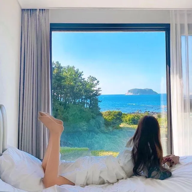 The bed by the window, with the sea and an island beyond the pine trees