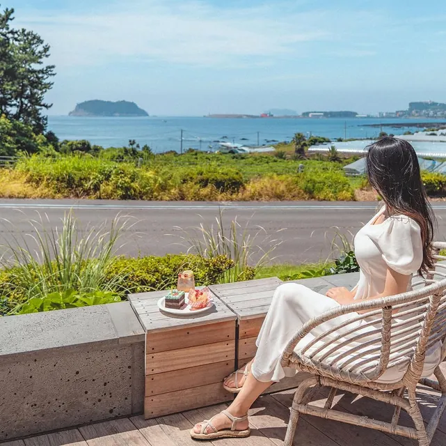 Relaxing in a rattan chair on a terrace overlooking the sea and an island